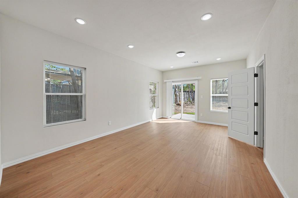 Spacious room featuring wood-finish flooring, recessed lighting, and multiple windows