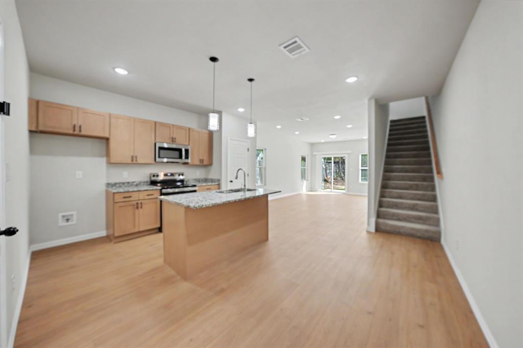 Open-concept living space featuring wood-finish flooring, recessed lighting, and a modern kitchen