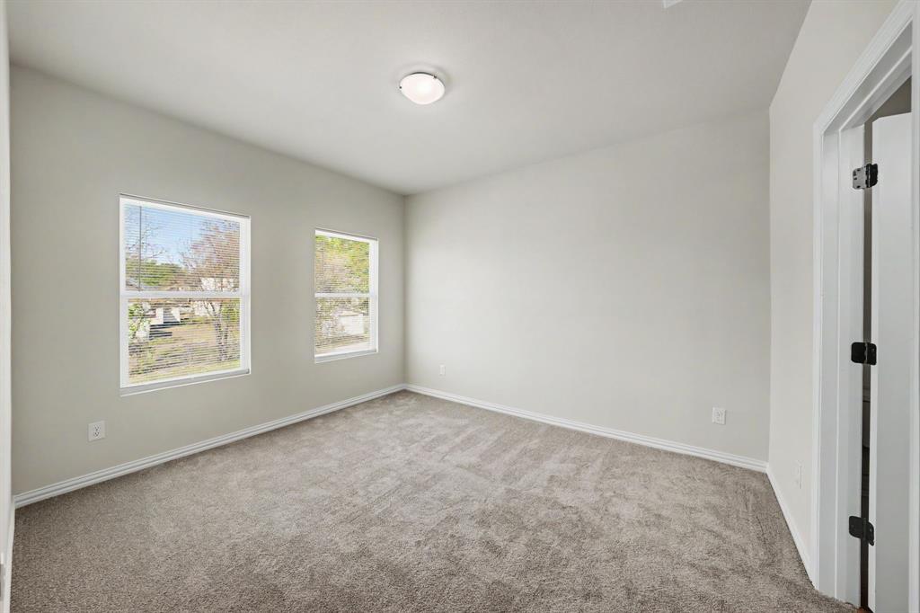 Neutral wall color, carpet flooring, two windows, and an overhead flush-mount light fixture