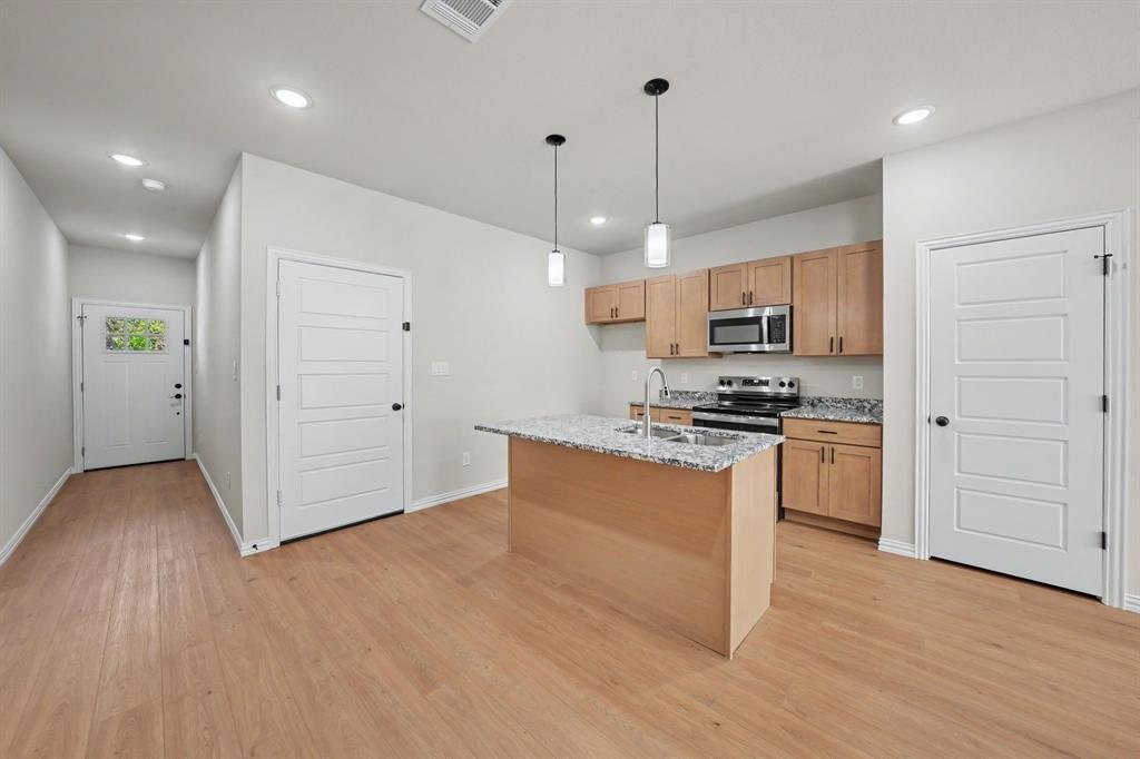 Wood-finish flooring throughout, kitchen island with granite countertop, stainless steel appliances, and recessed lighting