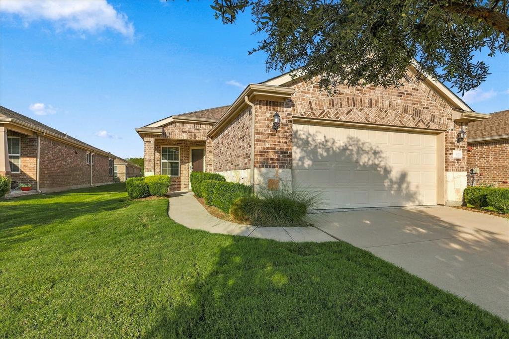Steel Creek Model with Brick and stone veneer exterior featuring an attached two-car garage, concrete driveway, and manicured landscaping