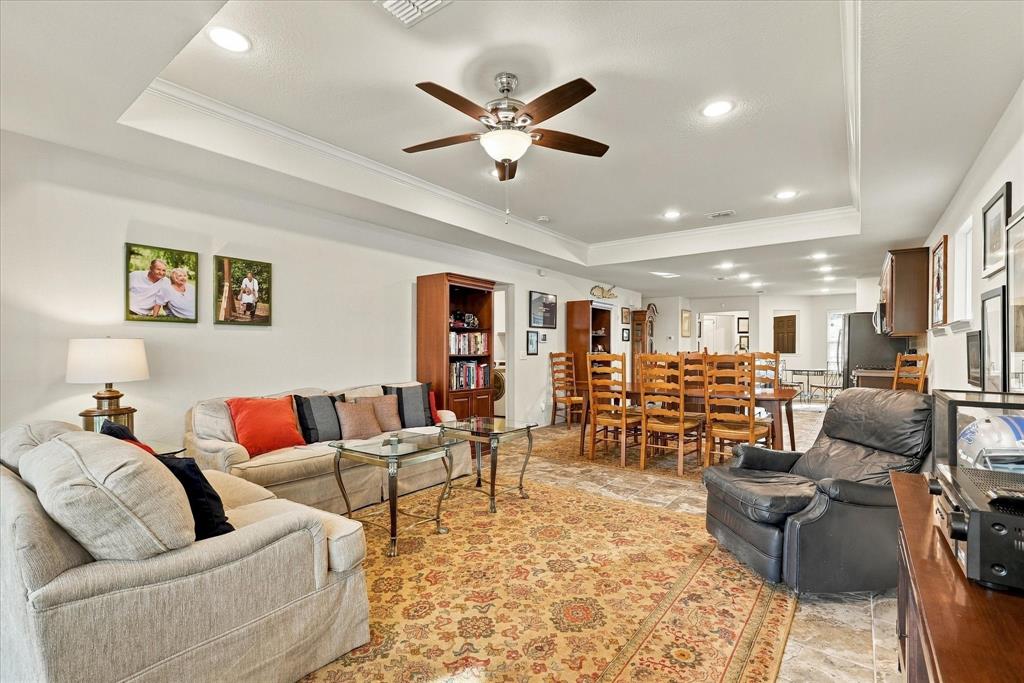 Tray ceiling with recessed lighting and a central ceiling fan, tile flooring