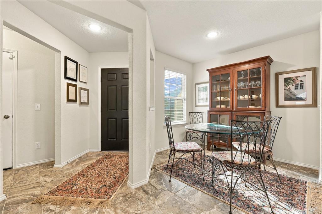 Foyer and dining area featuring natural stone tile flooring, recessed lighting, and a neutral color palette