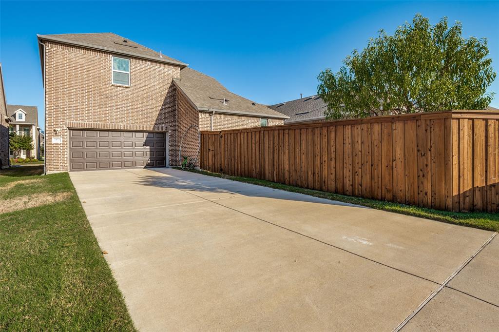 Two-story brick exterior featuring an attached two-car garage, concrete driveway, and full wood privacy fencing Two-story brick exterior featuring an attached two-car garage, concrete driveway, and full wood privacy fencing