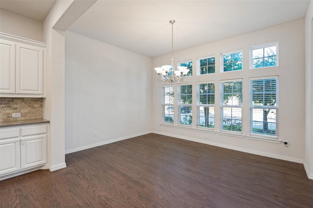 Wood-finish flooring, white shaker-style cabinetry with neutral tile backsplash, high ceilings, multi-pane window configuration, and an overhead multi-light chandelier