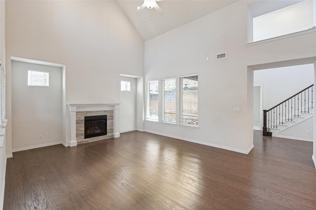 Vaulted ceilings, wood-finish flooring, stone-surround fireplace, and staircase with metal balusters