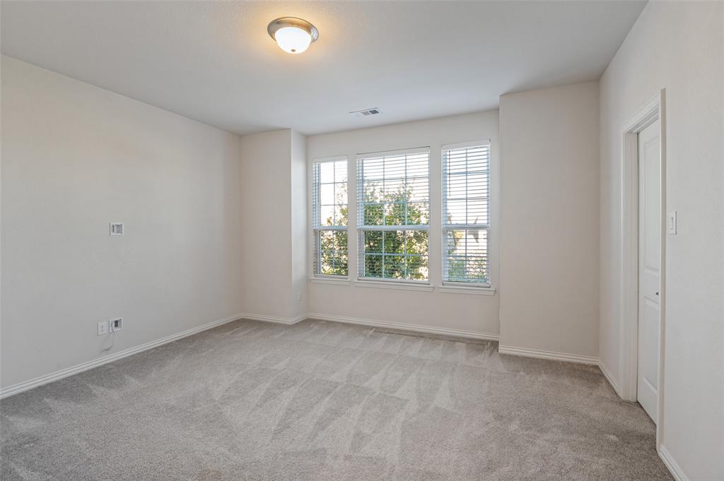 Neutral-toned wall paint, wall-to-wall carpeting, three-panel window configuration with horizontal blinds, and a flush-mount ceiling light fixture