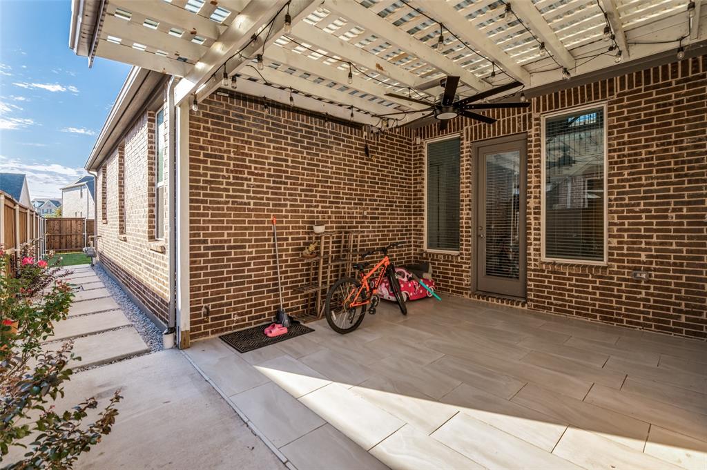 Covered patio featuring a brick exterior, large-format tile flooring, a slatted overhead pergola, and a ceiling-mounted fan Covered patio featuring a brick exterior, large-format tile flooring, a slatted overhead pergola, and a ceiling-mounted fan