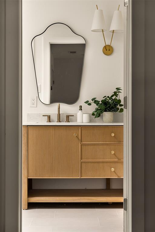 Luxuriously updated primary bathroom featuring a striking fluted wood double vanity, elegant brass fixtures, and designer mirrors