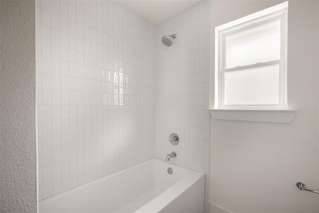 Fully updated secondary bathroom featuring a double vanity, refined finishes, decorative tile flooring, and a bright tub-shower surround with clean, timeless tilework.