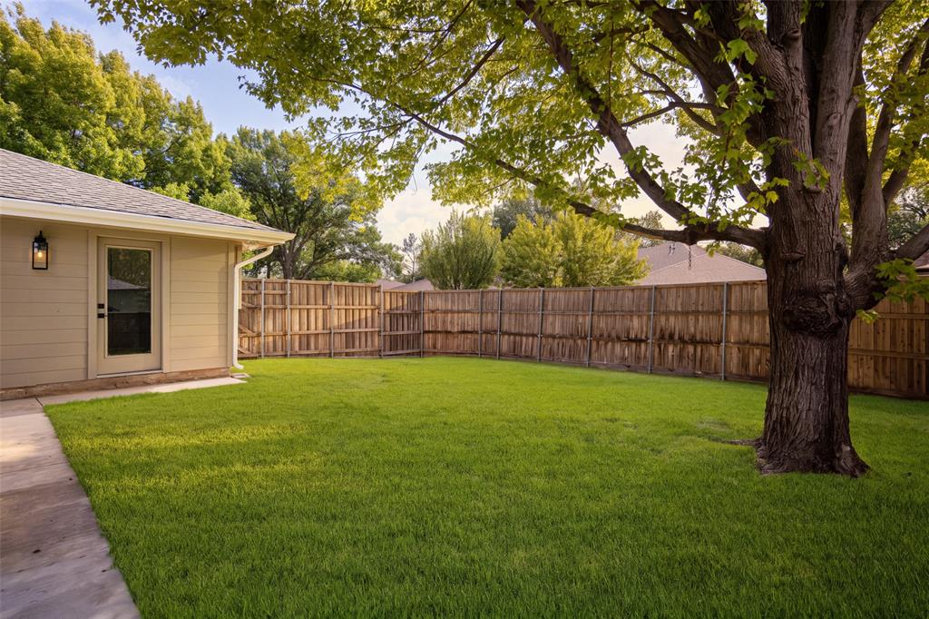 Expansive backyard with a spacious lawn, mature shade trees, privacy fencing, and a covered patio perfect for outdoor entertaining.