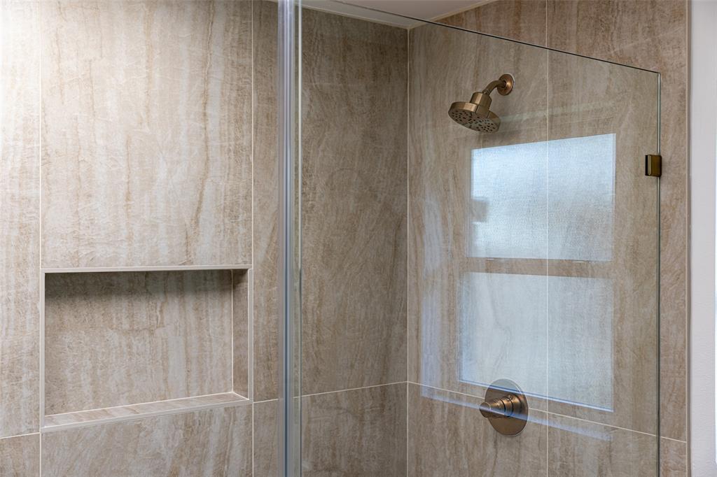 Spa-inspired primary bathroom featuring an expansive glass-enclosed shower with striking floor-to-ceiling tile, rich natural textures, and a seamless design that creates a serene, resort-like retreat.