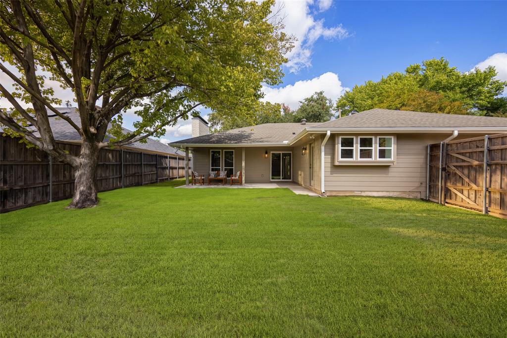 Expansive backyard with a spacious lawn, mature shade trees, privacy fencing, and a covered patio perfect for outdoor entertaining.