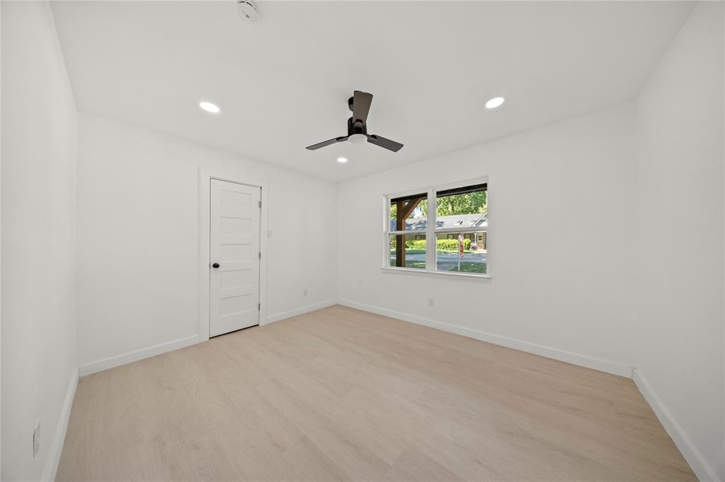 Interior room featuring neutral wall finishes, light-toned wood-finish flooring, a matte black ceiling fan, and a five-panel interior door