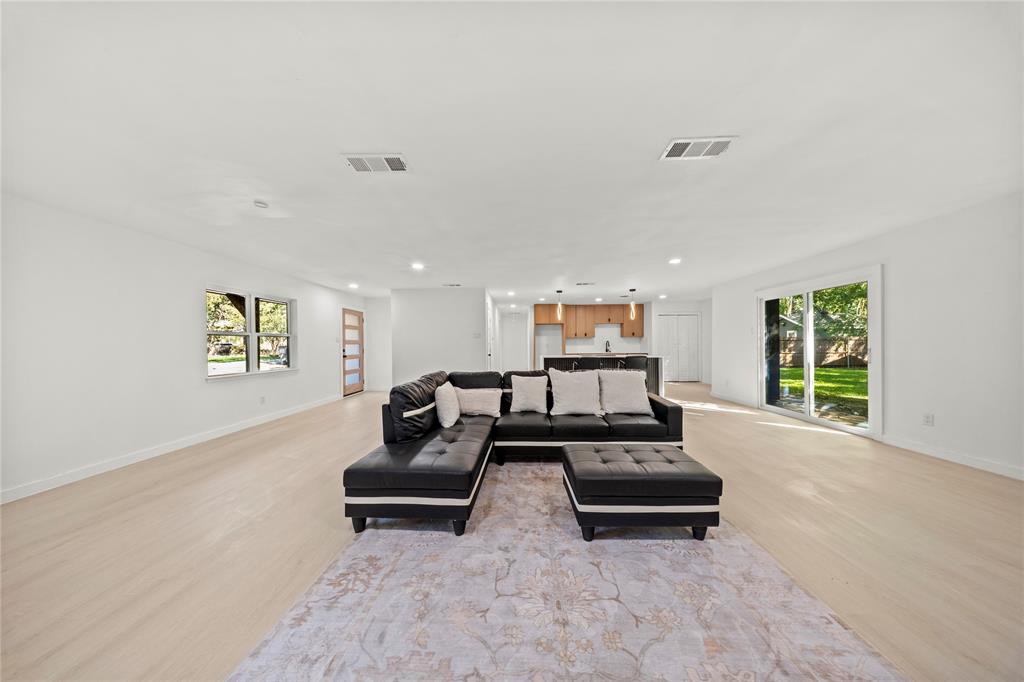 Open-concept interior featuring light wood-finish flooring, recessed lighting, sliding glass doors, and kitchen cabinetry with a kitchen island