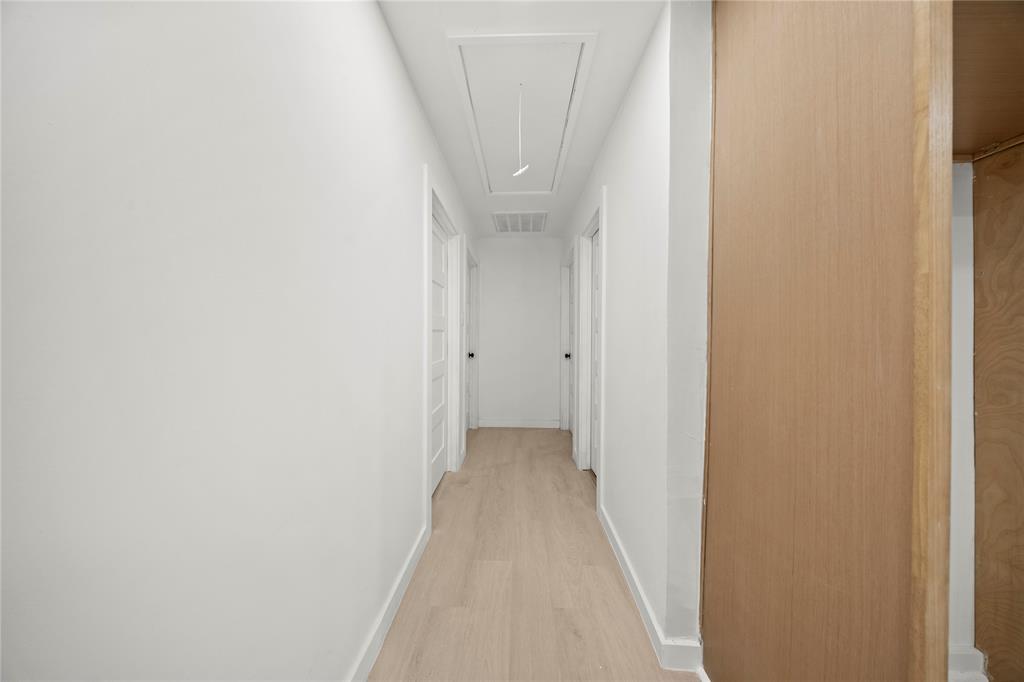 Hallway featuring wood-finish flooring, white walls, and multiple interior doors