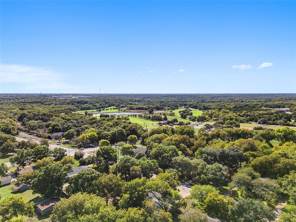 Aerial perspective of established canopy trees, expansive green space, and a pond