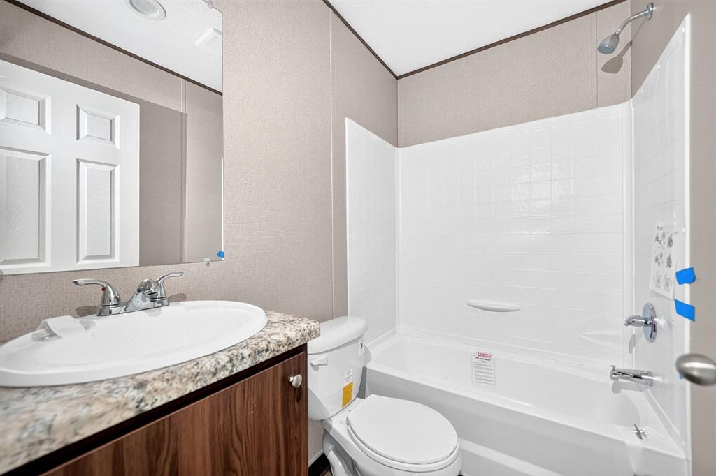 Bathroom featuring a vanity with a stone-finish countertop, undermount sink, and wood-finish cabinetry