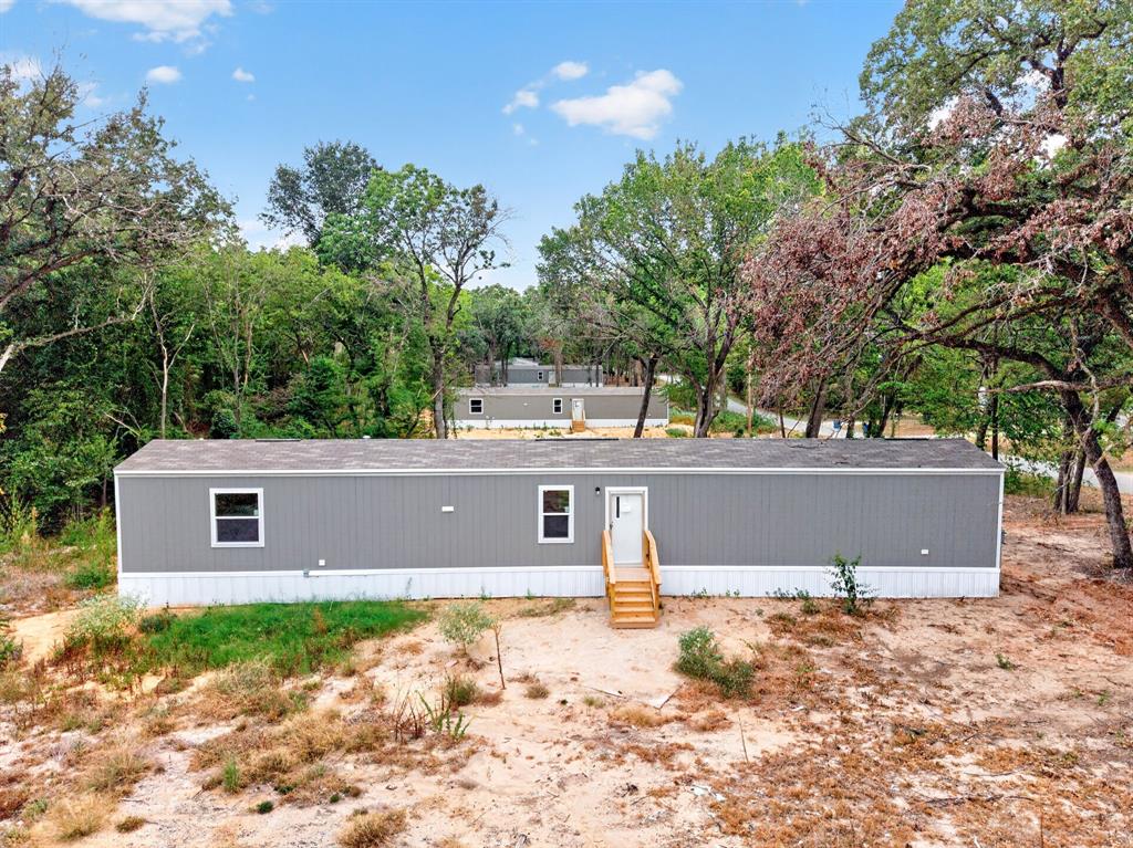 Gray manufactured home featuring a white trim, multiple windows, and a wooden entry staircase Gray manufactured home featuring a white trim, multiple windows, and a wooden entry staircase