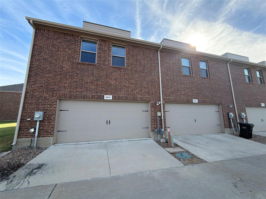 Multi-story brick exterior featuring attached dual-car garages, concrete driveways, and rectangular windows Multi-story brick exterior featuring attached dual-car garages, concrete driveways, and rectangular windows