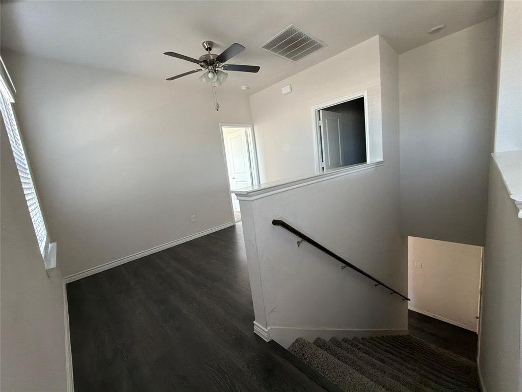 Open-concept landing featuring wood-finish flooring, a ceiling fan with integrated lighting, carpeted stairs, and a dark-finish handrail