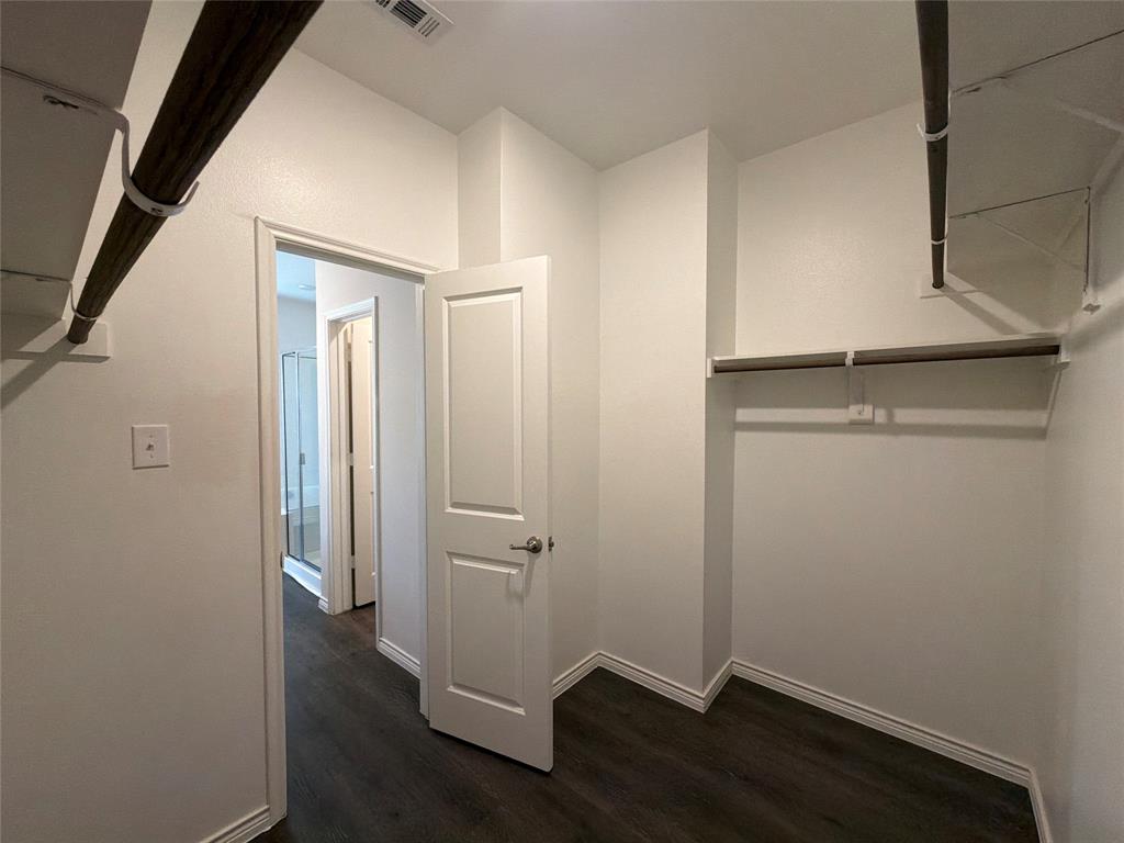 Walk-in closet featuring wood-finish flooring, built-in shelving, and dual hanging rods