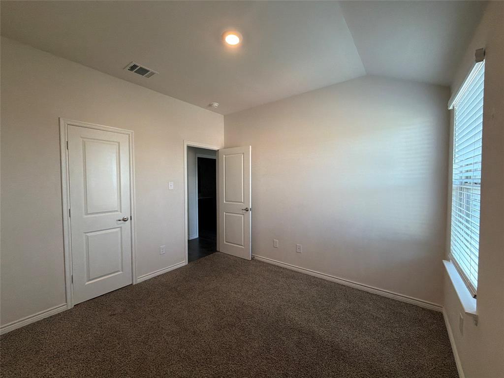 Vaulted ceiling, neutral wall tones, carpeted flooring, two interior panel doors, and window with slatted blinds