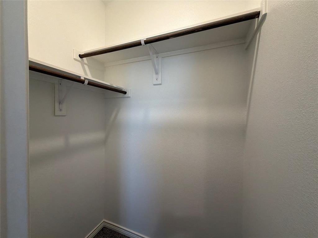 Walk-in closet featuring dual-level shelving and sturdy rods