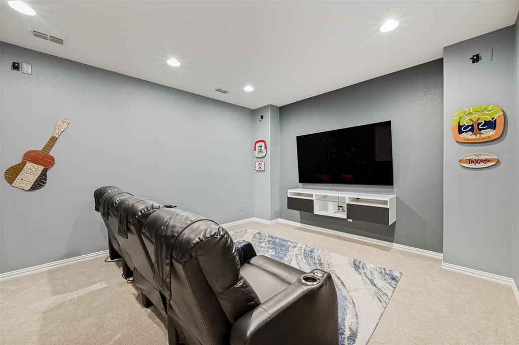 Recessed ceiling lighting illuminates a media wall featuring a mounted television and a floating entertainment console
