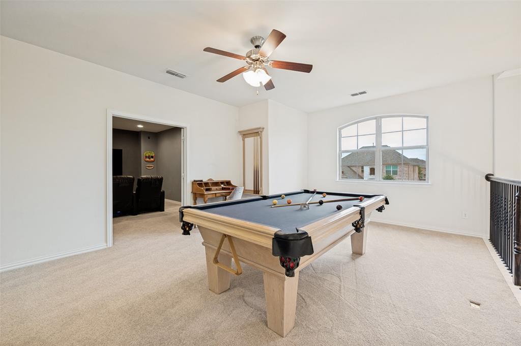 Carpeted room featuring a ceiling fan with light, an arched window, and a wrought iron railing