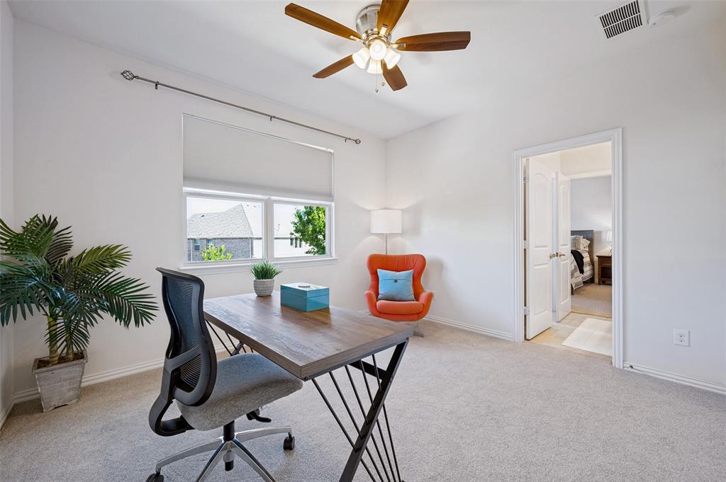 Room with neutral carpeting, multi-pane window with roller shade, ceiling fan with integrated lighting, and white interior doors