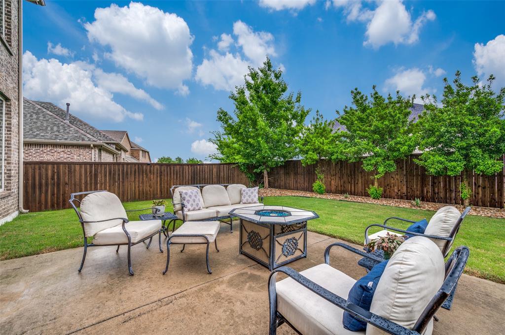 Private backyard featuring a concrete patio, wood privacy fence, and manicured lawn with mature trees