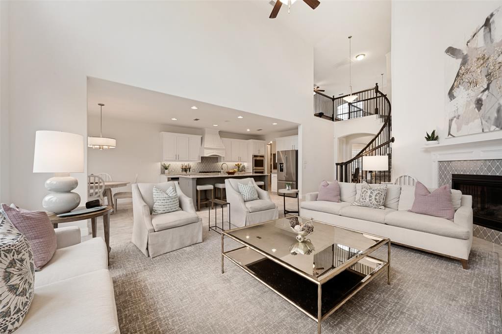 High ceilings, open-concept design, fireplace with tile surround, spiral staircase with wrought iron railing, and a kitchen with an island and stainless steel appliances