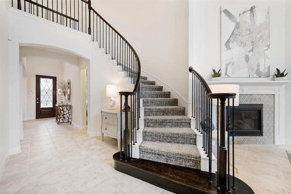 Curved staircase with iron balusters, carpeted treads, and wood handrail