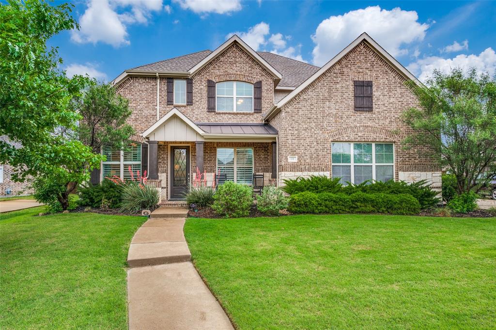 Two-story brick exterior with stone accents, covered front porch, and mature landscaping