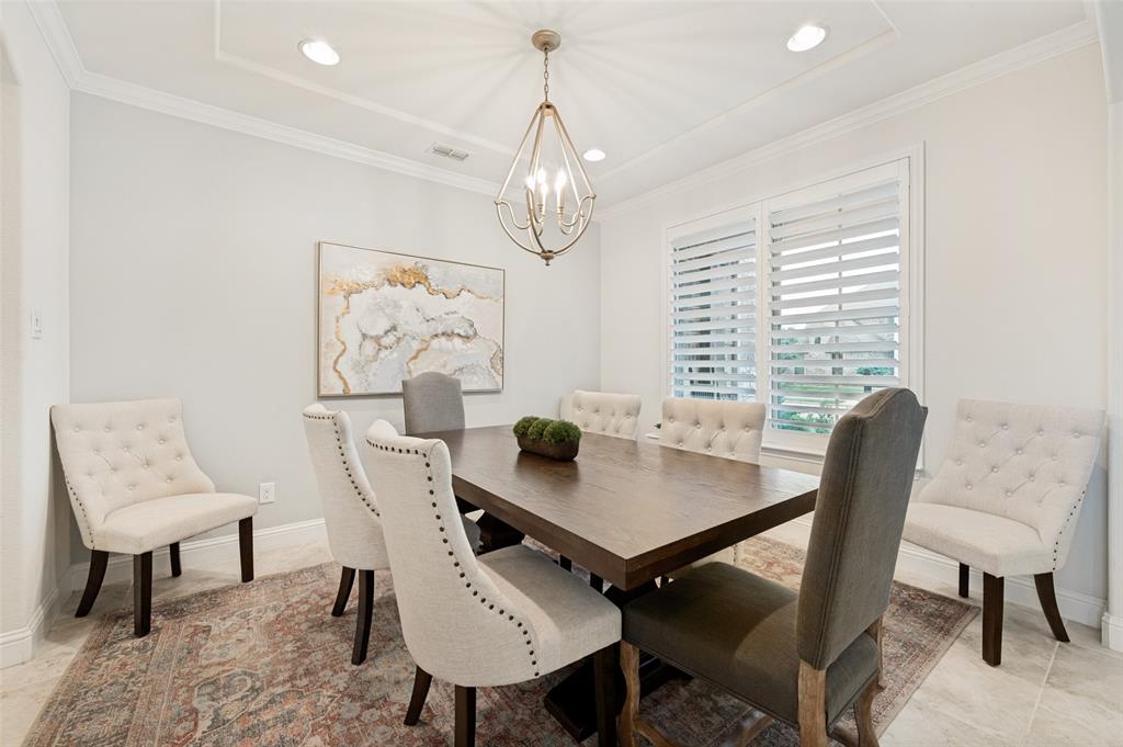 Tray ceiling with recessed lighting, crown molding, plantation shutters, and tile flooring