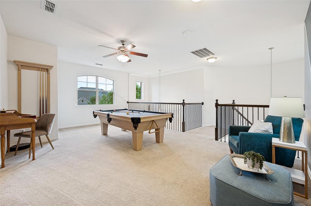 Expansive carpeted loft space featuring an arched window, ceiling fan with light, and open railings