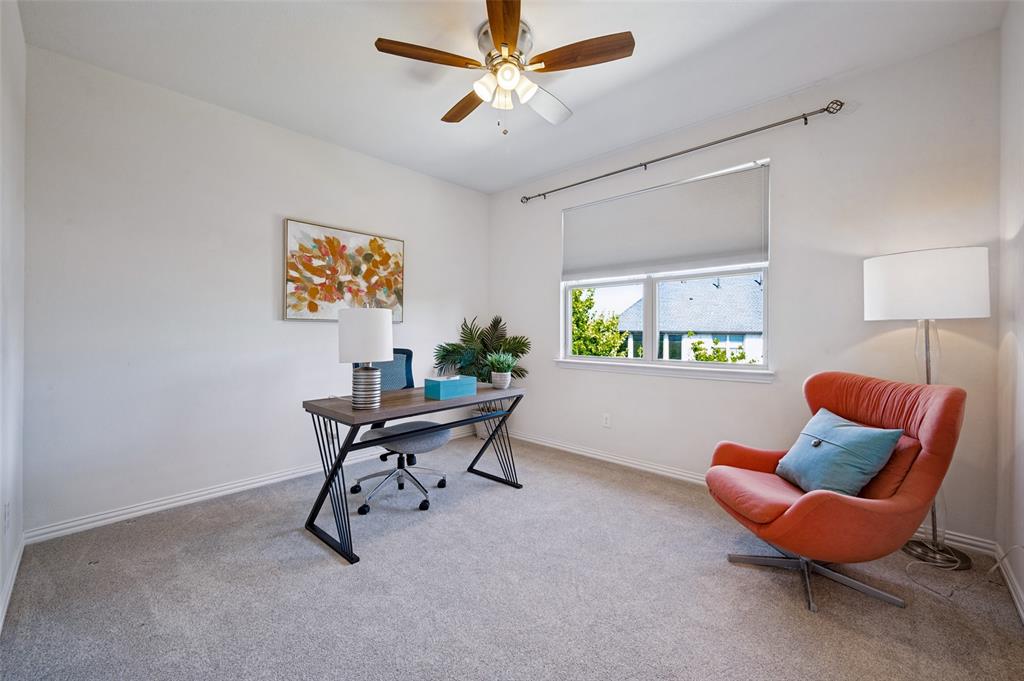 Neutral-toned carpeted room featuring a ceiling fan with integrated lighting, window with a roller shade, and drapery hardware