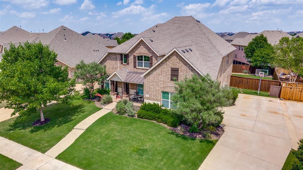 Brick exterior with a covered entry, mature landscaping, and a concrete driveway