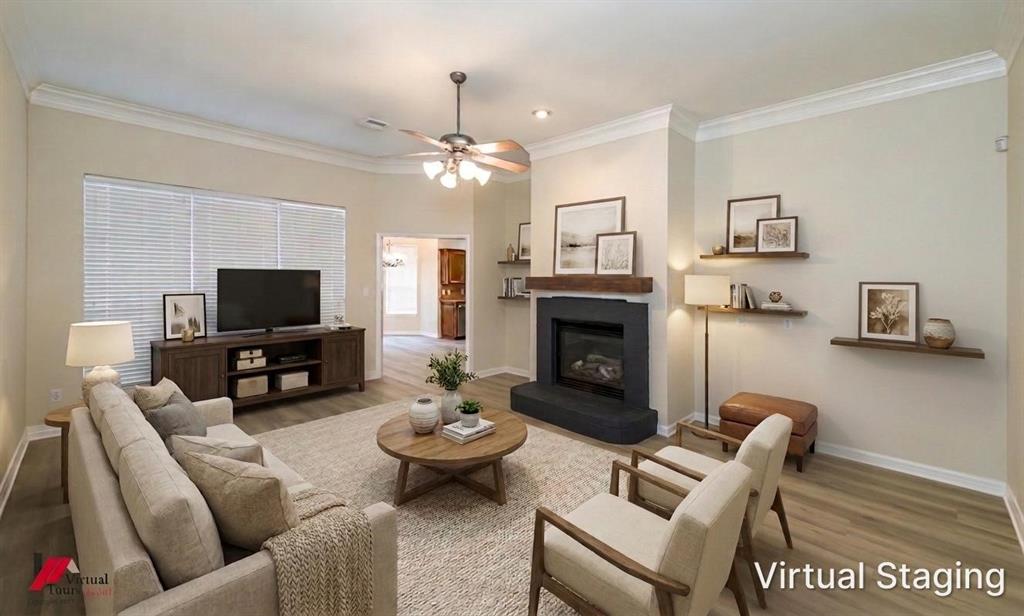 Virtually staged. Living area featuring wood-finish flooring, a fireplace with a black surround, a wood mantel, crown molding, and recessed lighting