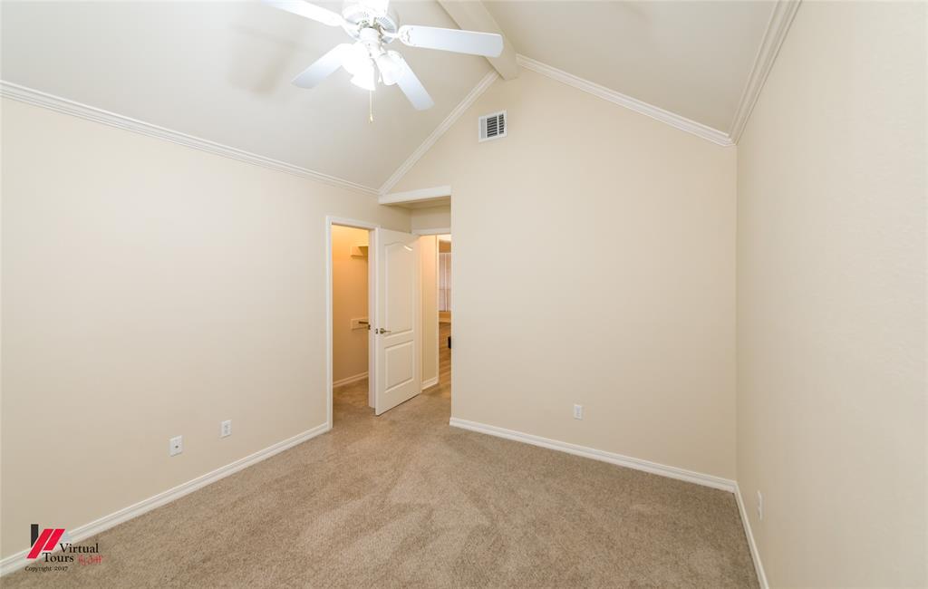 Vaulted ceilings, neutral carpeted flooring, and a white ceiling fan with integrated lighting