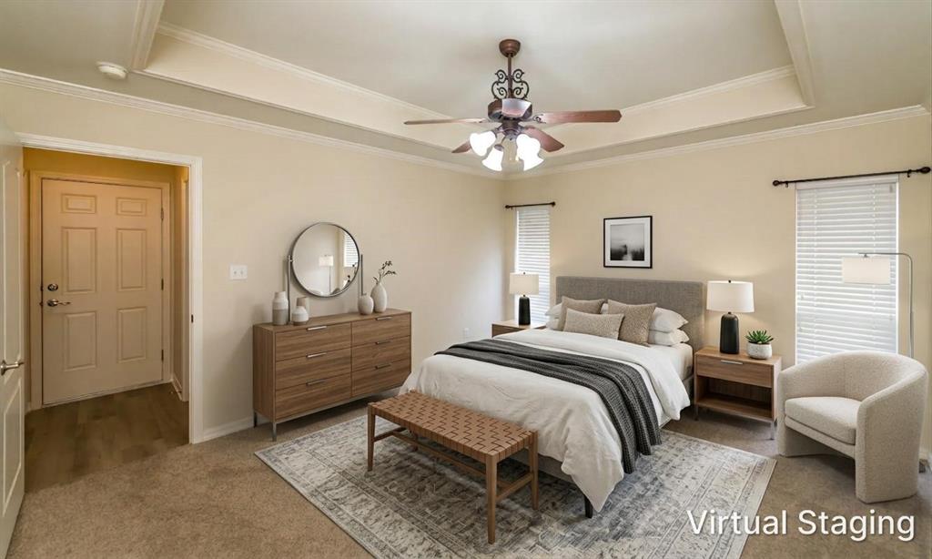 Virtually staged. Tray ceiling with crown molding, neutral wall tones, carpeted flooring, and a decorative ceiling fan with integrated lighting