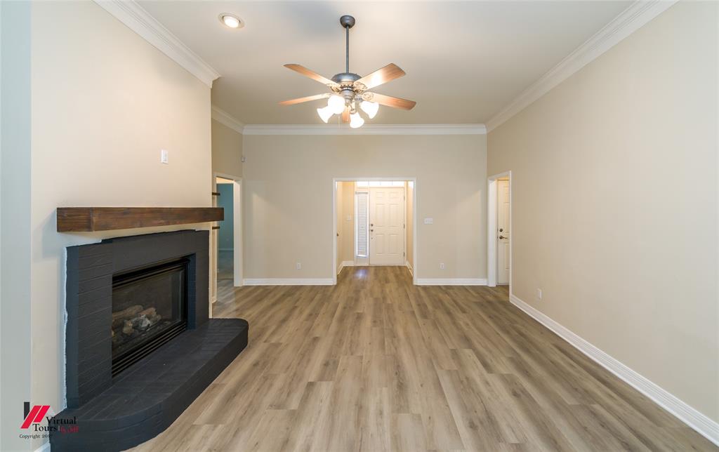 Living area featuring wood-finish flooring, a fireplace with a black tile surround and wood mantel, recessed lighting, and crown molding