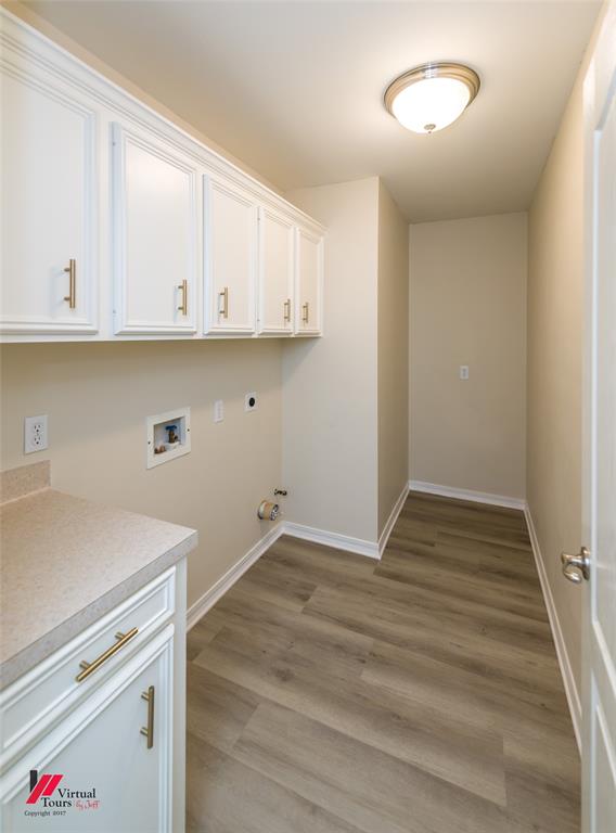 Utility space featuring wood-finish flooring, white cabinetry with brushed-metal pulls, and a solid-surface countertop with an integrated sink basin