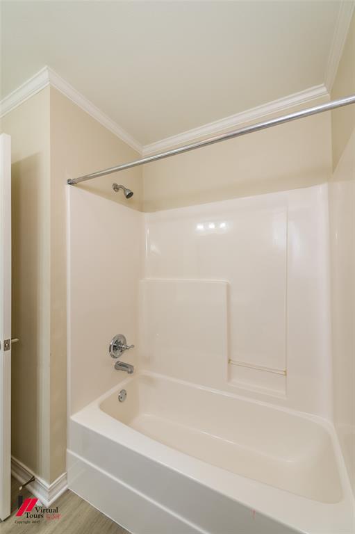 Full-size shower and bathtub combination with molded surround, polished chrome hardware, and crown molding