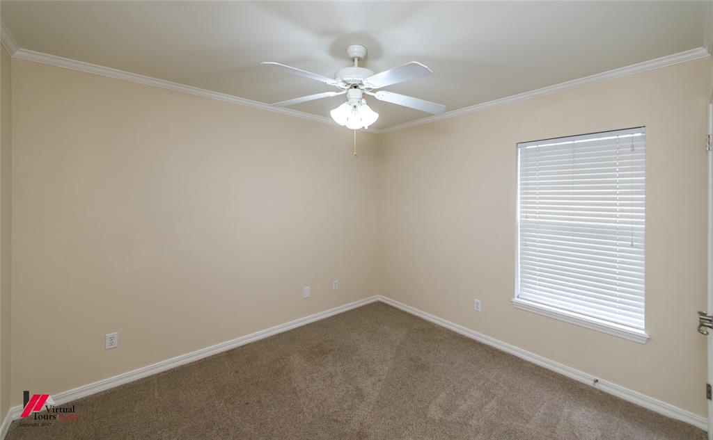 Neutral-toned interior featuring wall-to-wall carpeting, crown molding, a ceiling fan with integrated light fixture, and a window with horizontal blinds