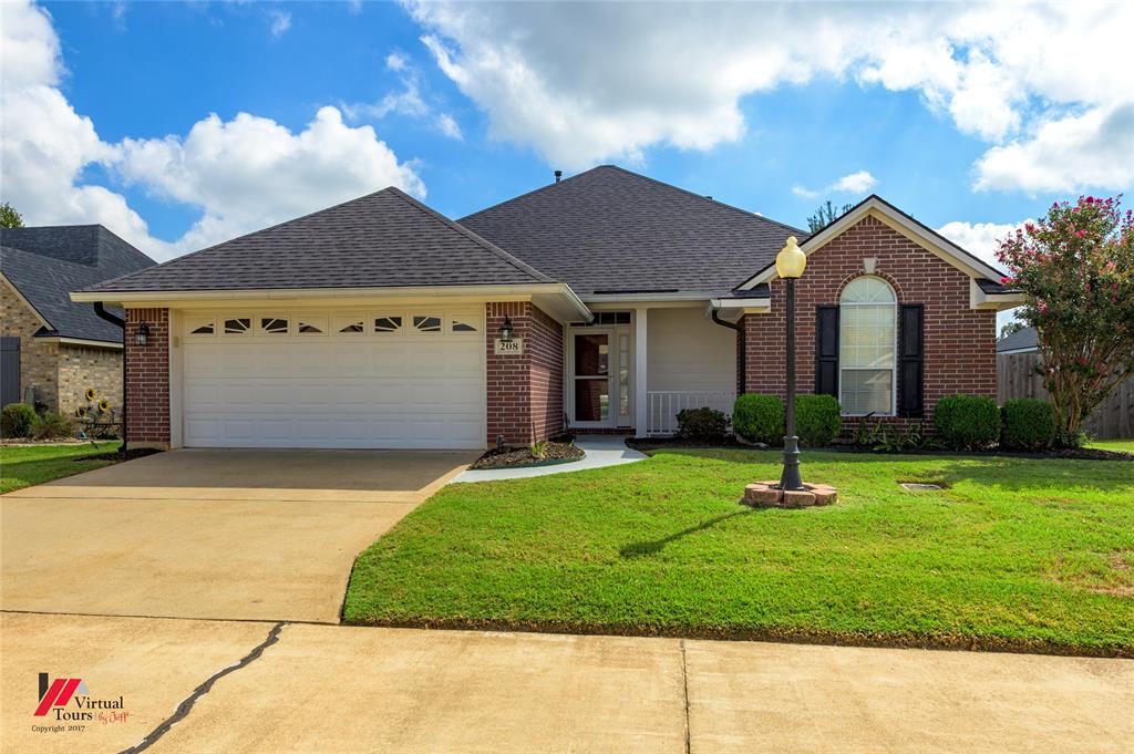 Brick exterior featuring a hip roof, arched window with decorative muntins, two-car garage, and post-mounted outdoor lighting