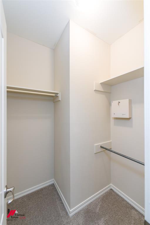 Walk-in closet featuring wall-to-wall carpeting, dual-level hanging rods, and an overhead shelf