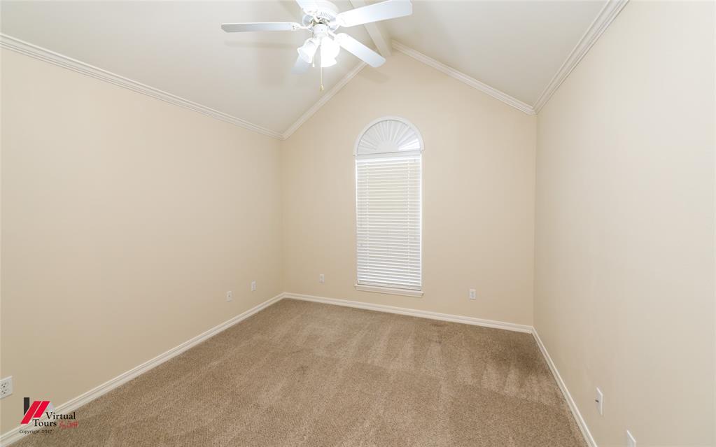 Vaulted ceiling featuring a central ceiling fan with integrated lighting, a tall window topped with an arched transom, and neutral carpeting