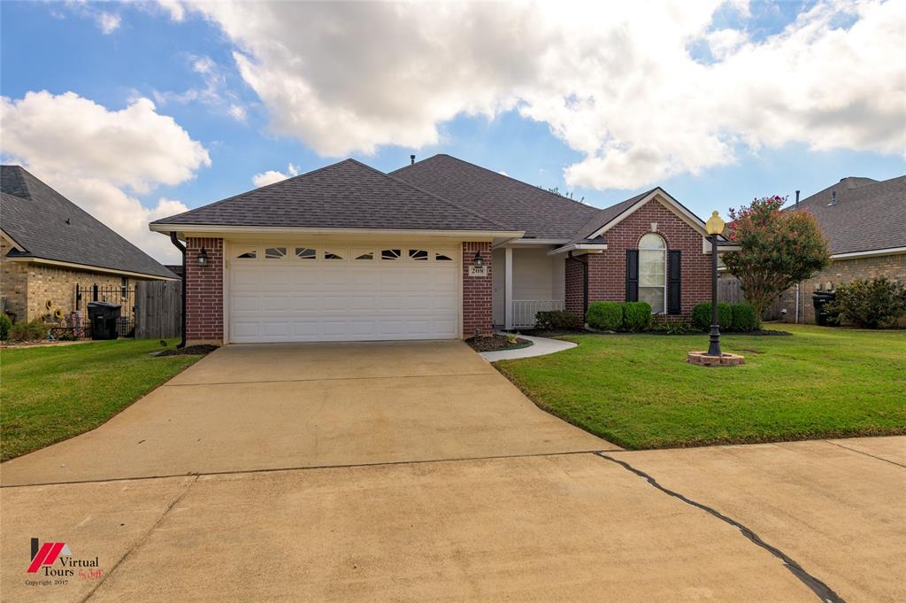 Single-story brick exterior featuring a double-car garage, arched window, concrete driveway, and manicured front lawn